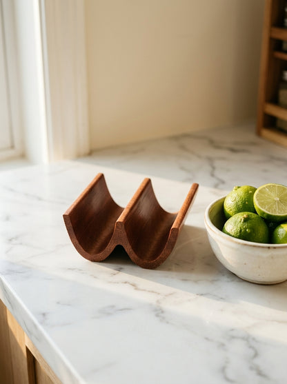 Solid mahogany double taco holder on marble countertop with bowl of limes and halved lime