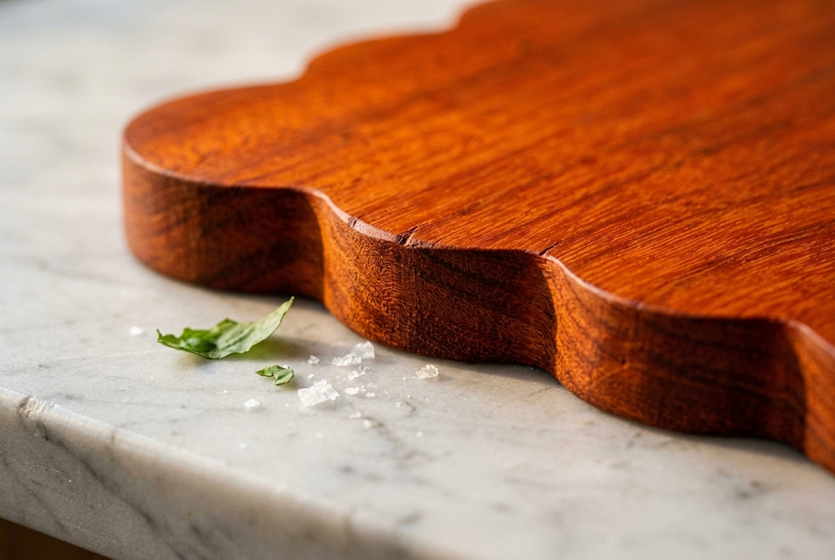 Close up padauk scalloped edge detail showing hand carved wavy curves with sea salt and basil on marble macro photography