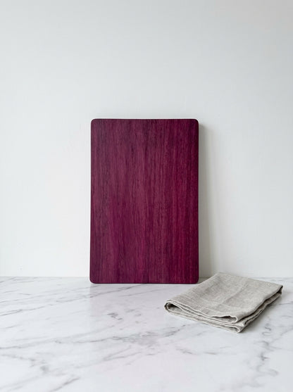 Purple heart cutting board upright with linen towel