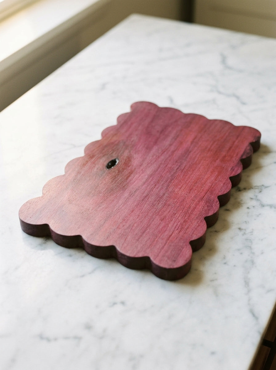 Solid purpleheart scalloped board showing natural knot and violet grain, flat on marble surface
