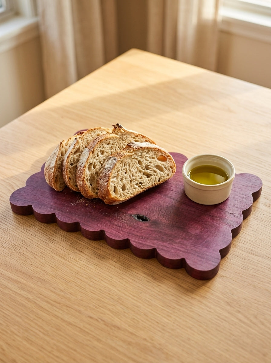 Purpleheart scalloped board with sliced sourdough and olive oil ramekin on natural wood table